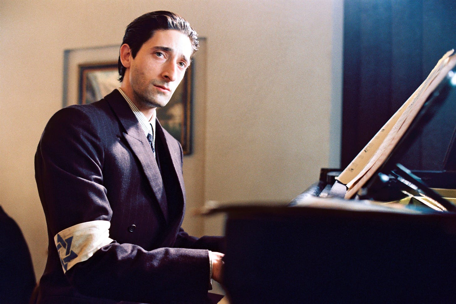 A man wearing an armband with the Star of David plays a piano