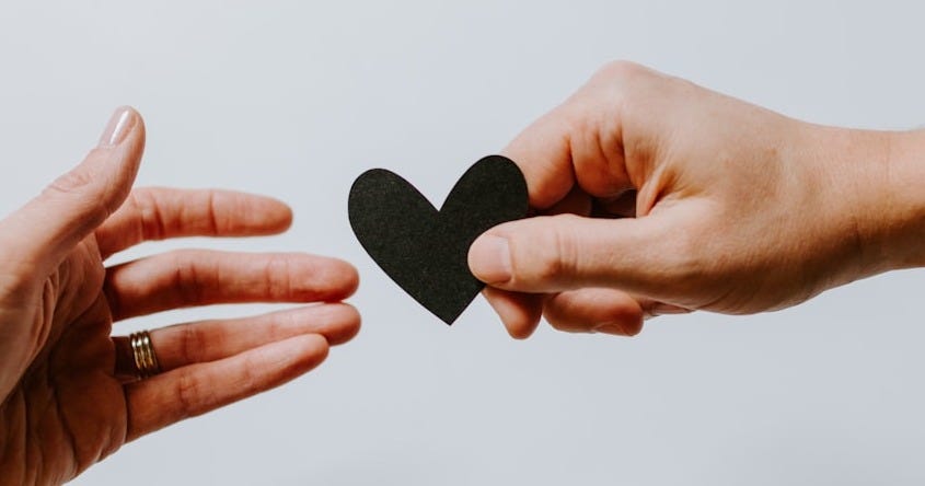 person reaching black heart cutout paper person reaching black heart cutout paper