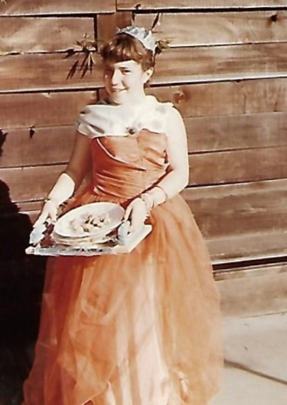 The author’s sister as Queen Esther, sharing food treats with neighbors, 1961.