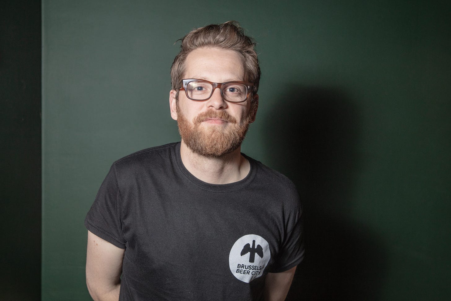 Photograph of Eoghan Walsh, in black tshirt on a green background