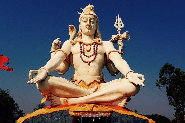 A statue of Shiva, in meditation pose, two arms on his knees, two arms at his sides, and a snake around his neck
