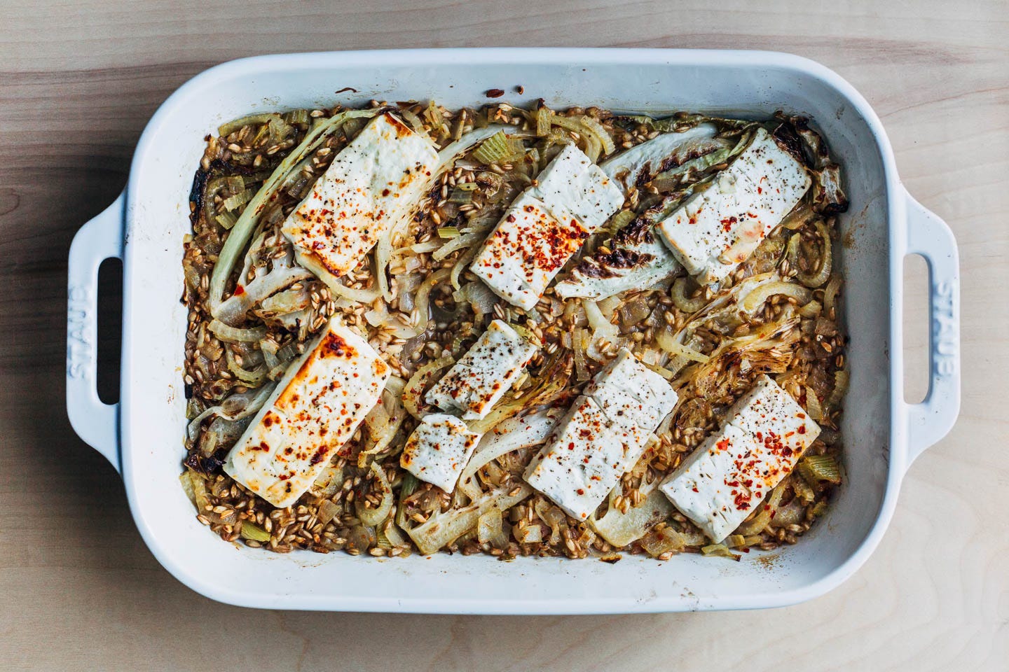 A baking dish with baked farro and feta