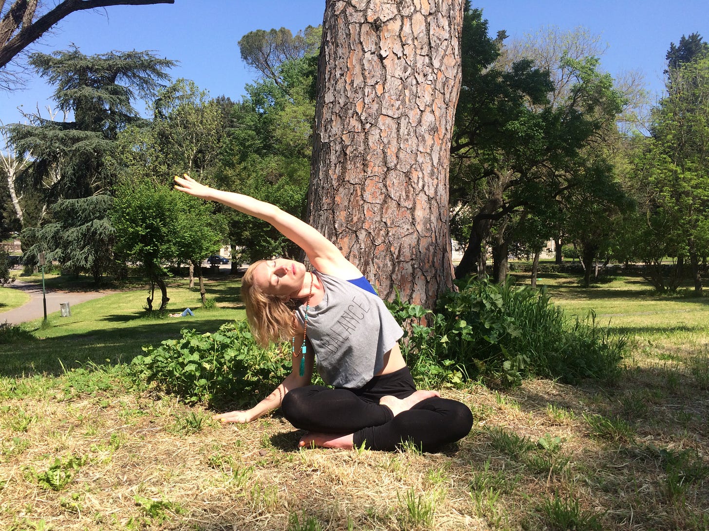 Jade doing a seated side stretch in a park