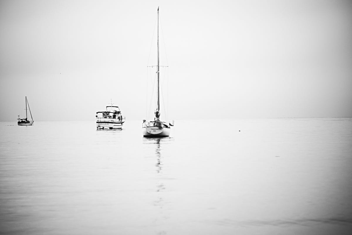 Two sailboats and a motor yacht anchored off Santa Barbara's East Beach in a fog