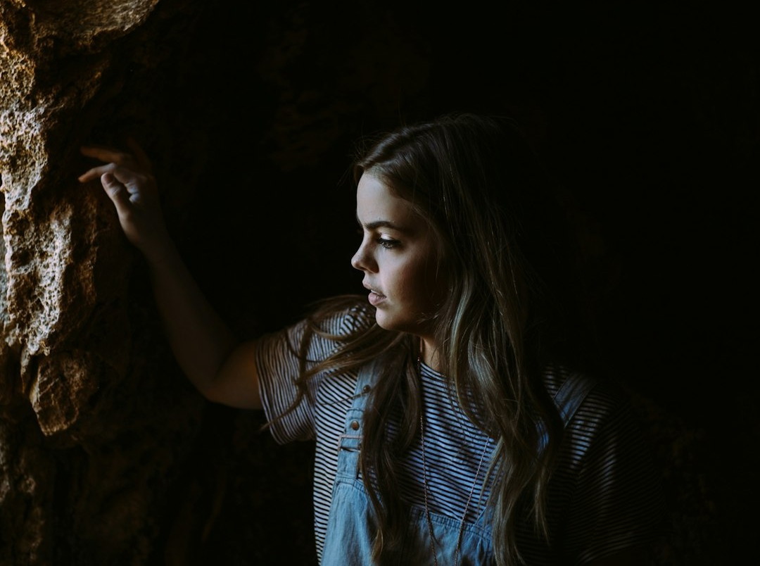 girl wearing blue and white dress holding on brown rocks girl wearing blue and white dress holding on brown rocks