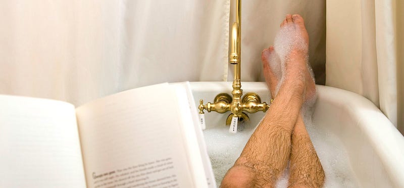 Man’s hairy legs, bubble bath, brass faucet, book