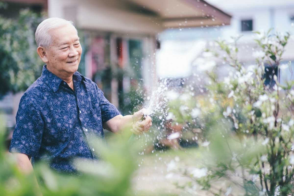 Elder gentleman enjoying his time watering his garden.