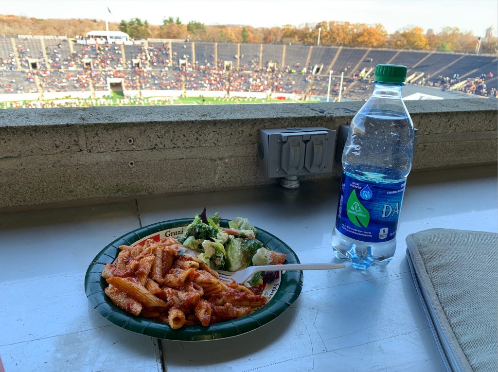 plate of ziti and salad with a water bottle on the side