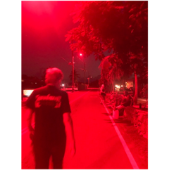 A person standing on a street with a red light

Description automatically generated