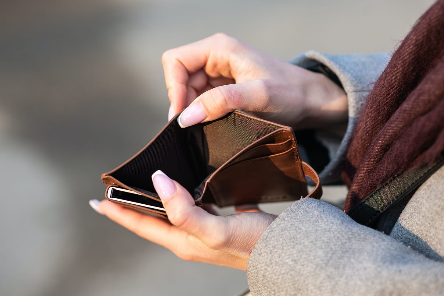 A person holding a wallet open, showing it is empty
