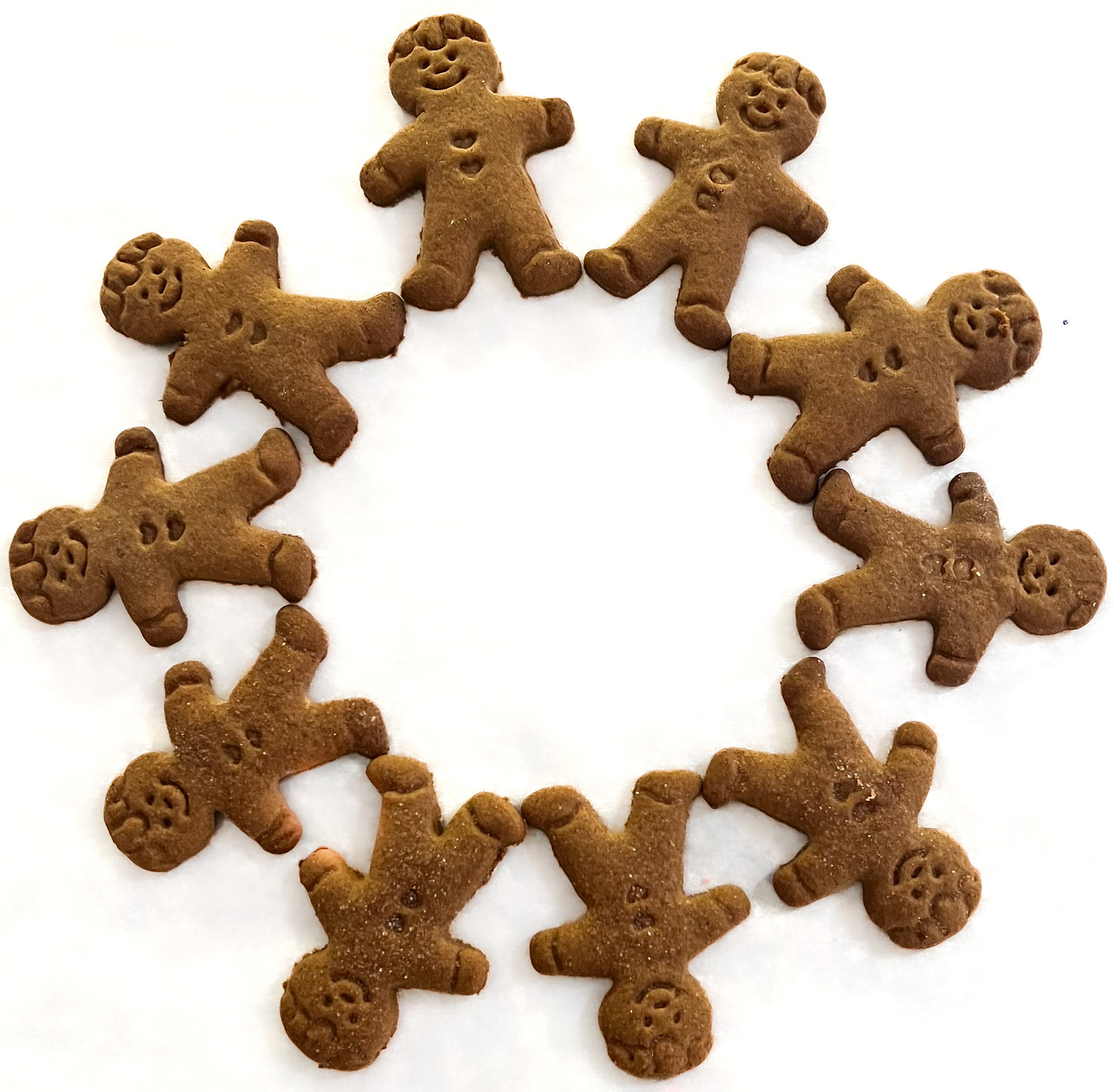 Small gingerbread man cookies layed out in a circle against a white background