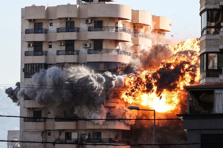 Smoke and flames rise after an Israeli strike on a building in the Chiyah district of Beirut's southern suburbs, as people watch,