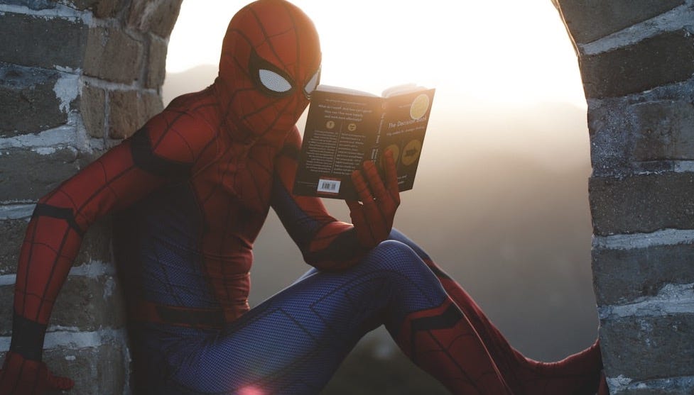 Spider-Man leaning on concrete brick while reading book Spider-Man leaning on concrete brick while reading book