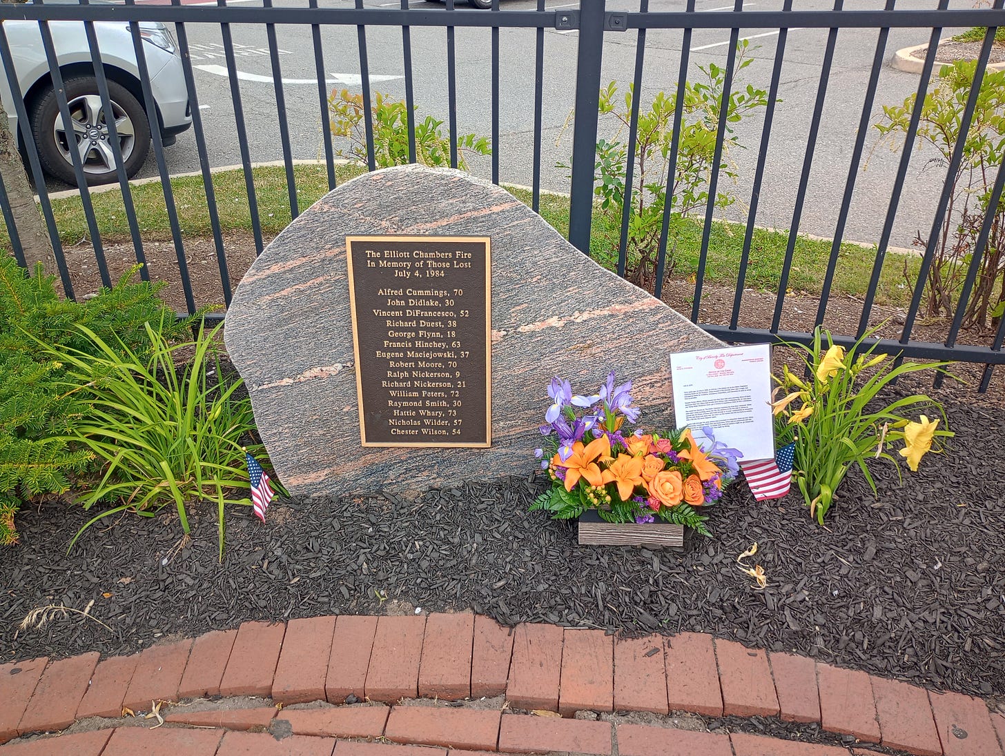 TEXT OF MONUMENT:  The Elliott Chambers Fire In Memory of Those Lost July 4, 1984  Alfred Cummings, 70 John Didlake, 30 Vincent DiFrancesco, 52 Richard Duest, 38 George Flynn, 18 Francis Hinchey, 63 Eugene Maciejowski, 37 Robert Moore, 70 Ralph Nickerson, 9 Richard Nickerson, 21 William Peters, 72 Raymond Smith, 30 Hattie Whary, 73 Nicholas Wilder, 57 Chester Wilson, 54