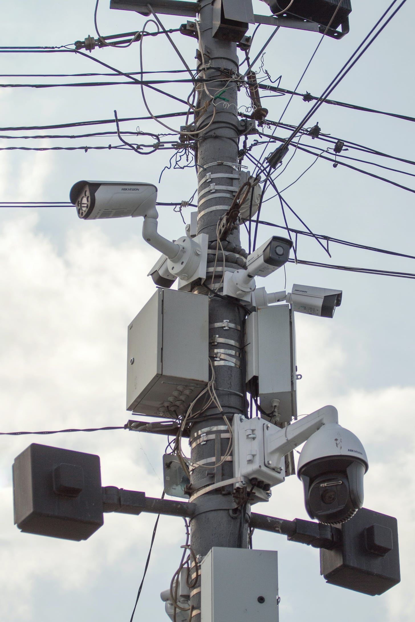 A photo of a utility pole with multiple surveillance cameras.