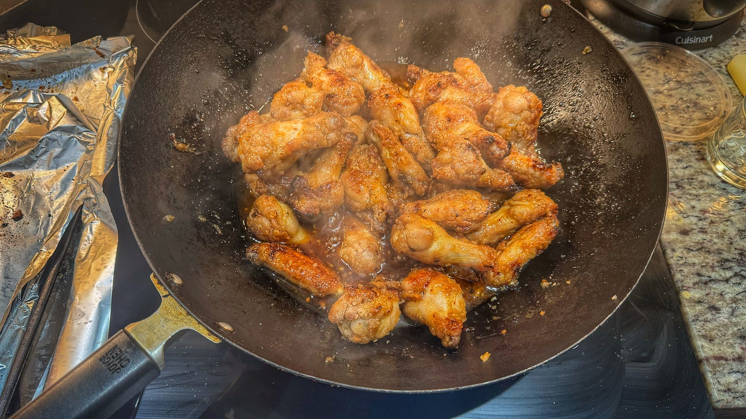 A wok containing fish sauce chicken wings being given a final glaze