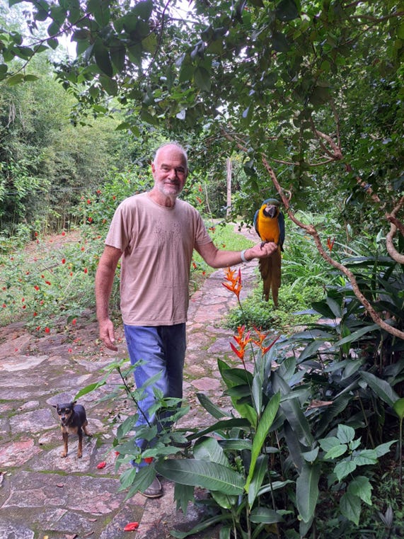 Dr Sircus gently holds a bird while standing on a stone path, embodying a moment of connection with nature.