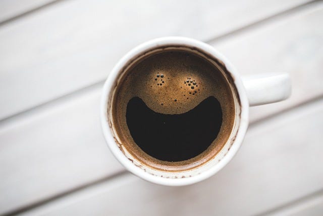 Photo of coffee from above where the bubbles have naturally formed a smiling face