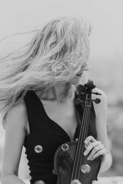 Free Black and white female musician holding music instrument while blowing hair on wind Stock Photo