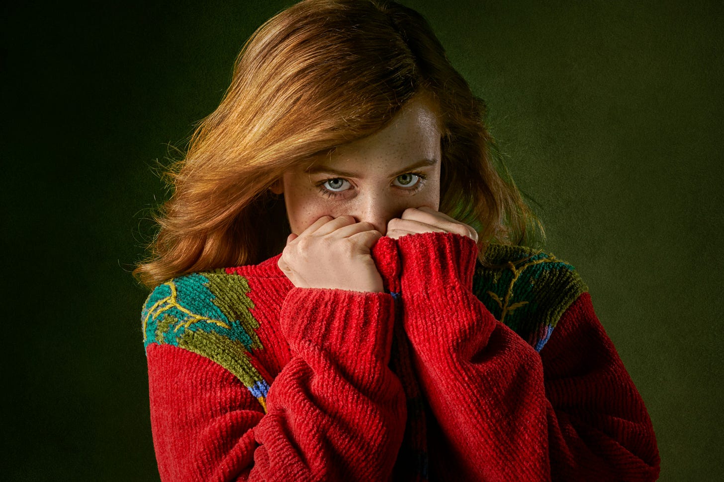 A shy redhead pulls the neck of her red sweater over her mouth