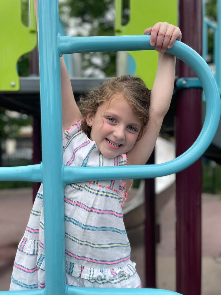 A little girl peeking through the rungs of a ladder