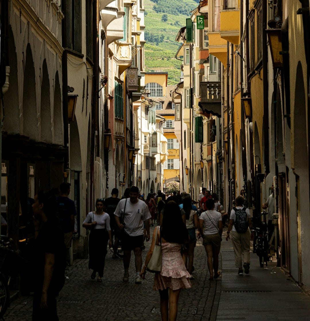 A group of people walking down a street next to tall buildings