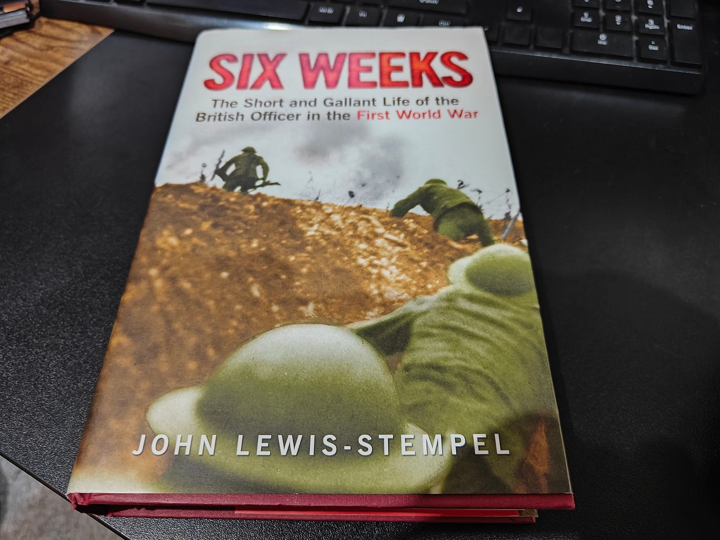 The book "Six Weeks - The short and gallant life of a British officer in the First World War" lying on a desk. A computer keyboard intrudes at the top of the photo. The book cover shows four British soldiers climbing from a trench and heading out into "no man's" land".