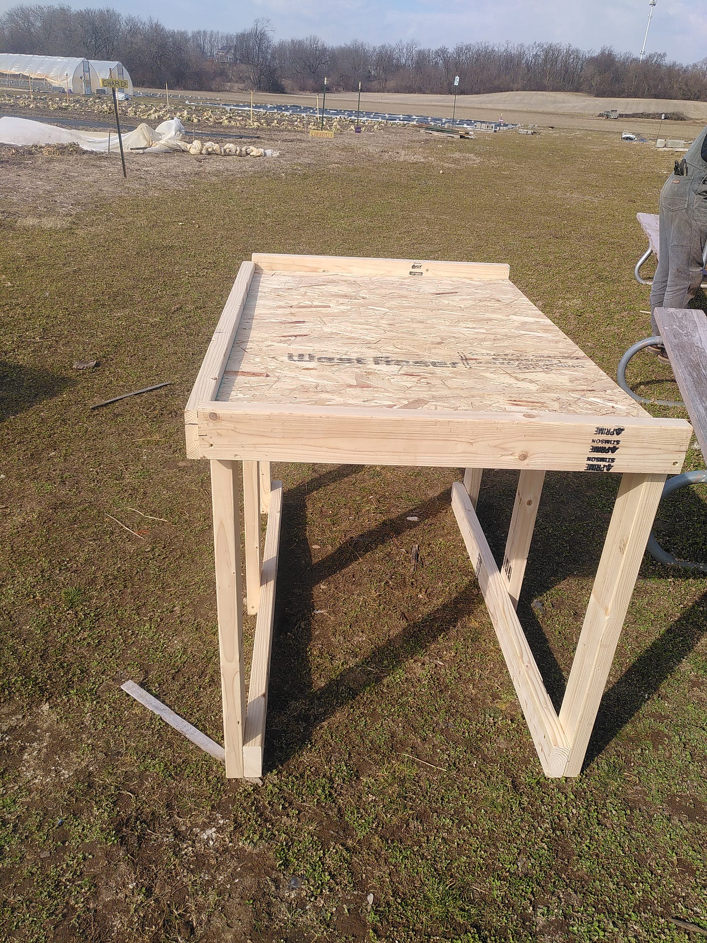 A table madde out of plywood and 2x4s outside on a farm.