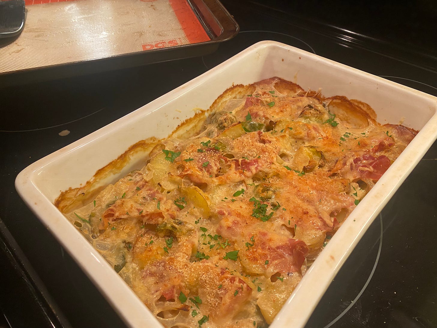 The gratin described above, in a white rectangular baking dish. It's got parsley and breadcrumbs on top and browned edges.