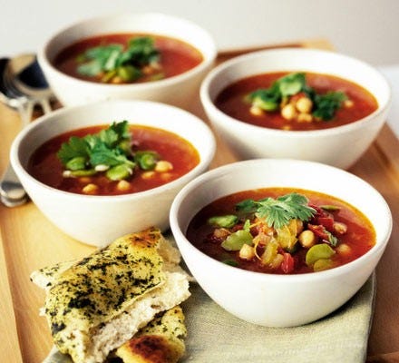 Moroccan chickpea soup in four bowls with naan bread