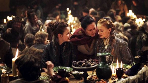 Three women at a feast in the Game of Thrones tv show.