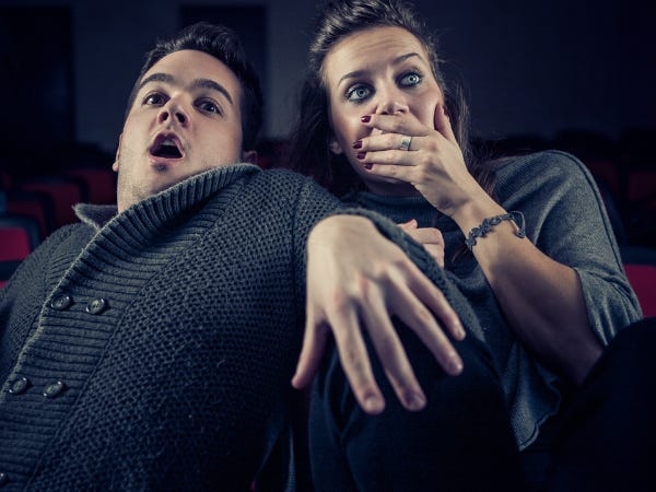 A white man and woman gasping in horror, the woman covering her face and both of them cowering