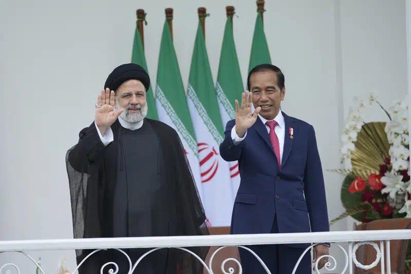 Iran's President Ebrahim Raisi, left, and Indonesian President Joko Widodo, right, wave to journalists during their meeting at the Presidential Palace in Bogor, West Java, Indonesia, Tuesday, May 23, 2023. (AP Photo/Achmad Ibrahim)