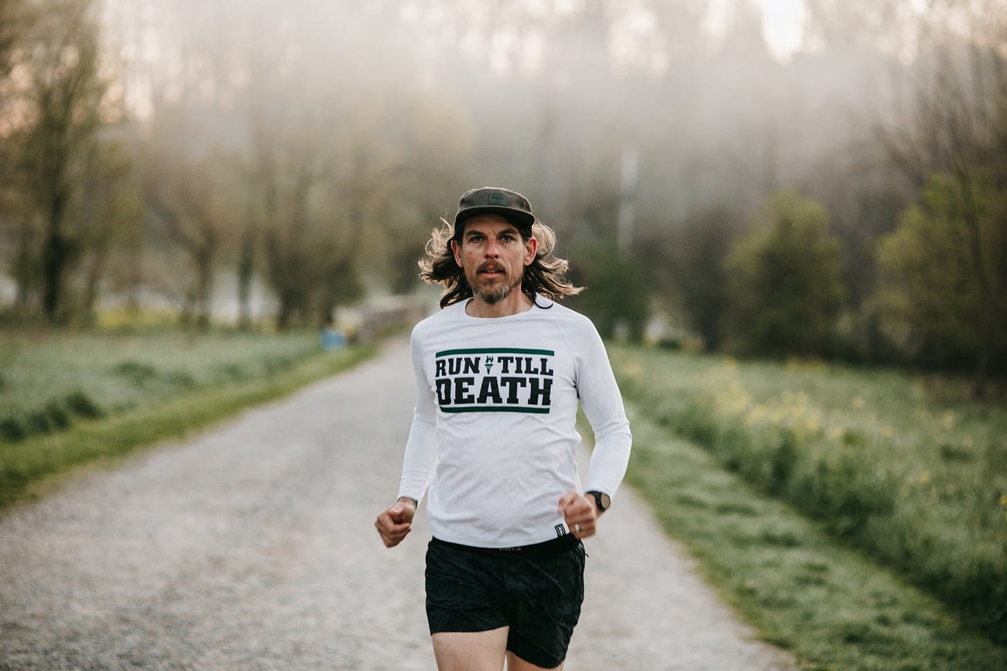 Läufer in der Natur, trägt ein weißes "Run Till Death" Shirt