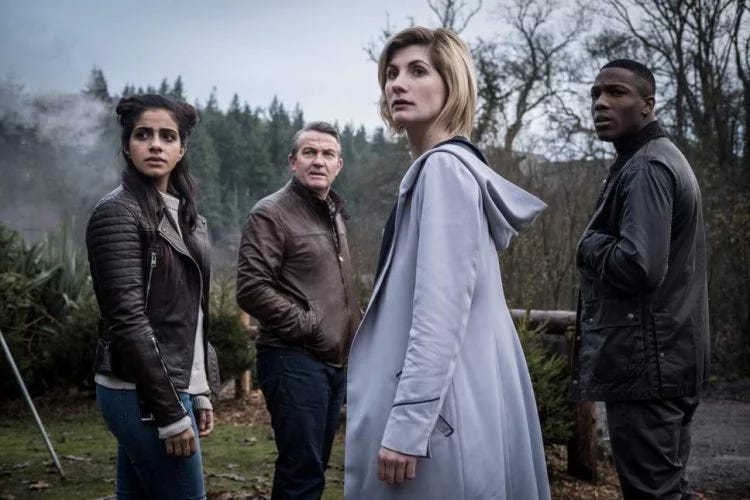 This image shows Team TARDIS standing in a 17th-Century Lancashire field in "The Witchfinders" (Doctor Who Series 11's eighth episode). From left to right: Yasmin "Yaz" Khan (played by Mandip Gill), Graham O'Brien (played by Bradley Walsh), the Thirteenth Doctor (played by Jodie Whittaker), and Ryan Sinclair (played by Tosin Cole).