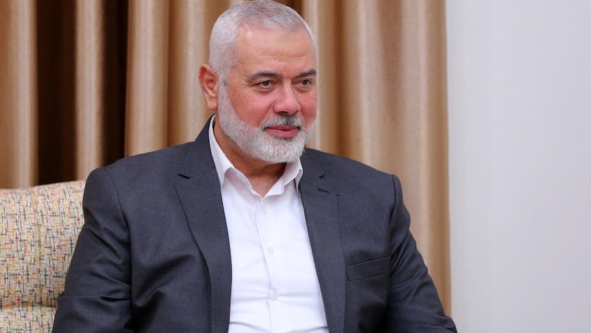 Ismail Haniyeh sitting on a chair with a curtain behind him. 