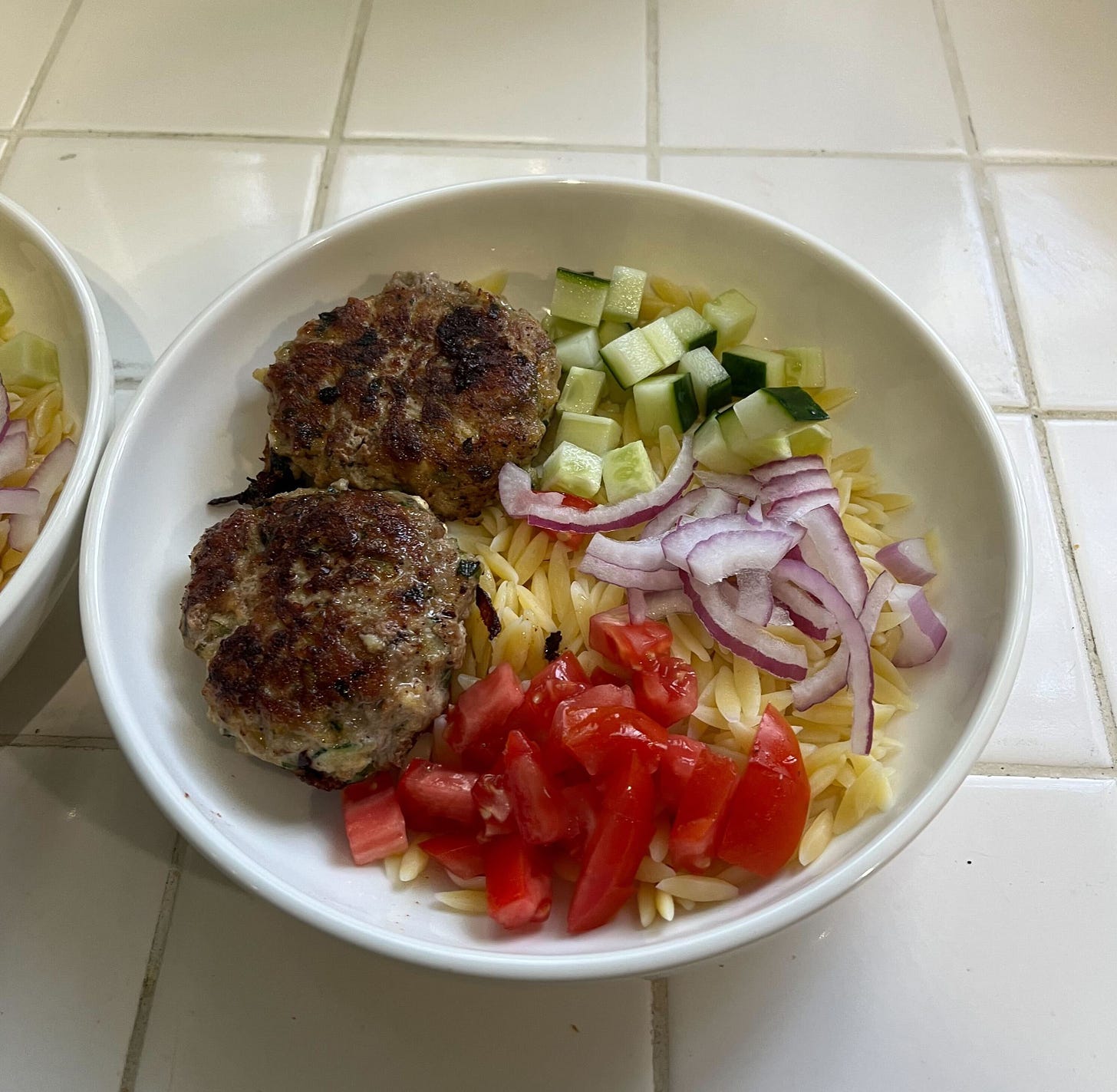 Pork patties with orzo, tomatoes, cucumber and red onion