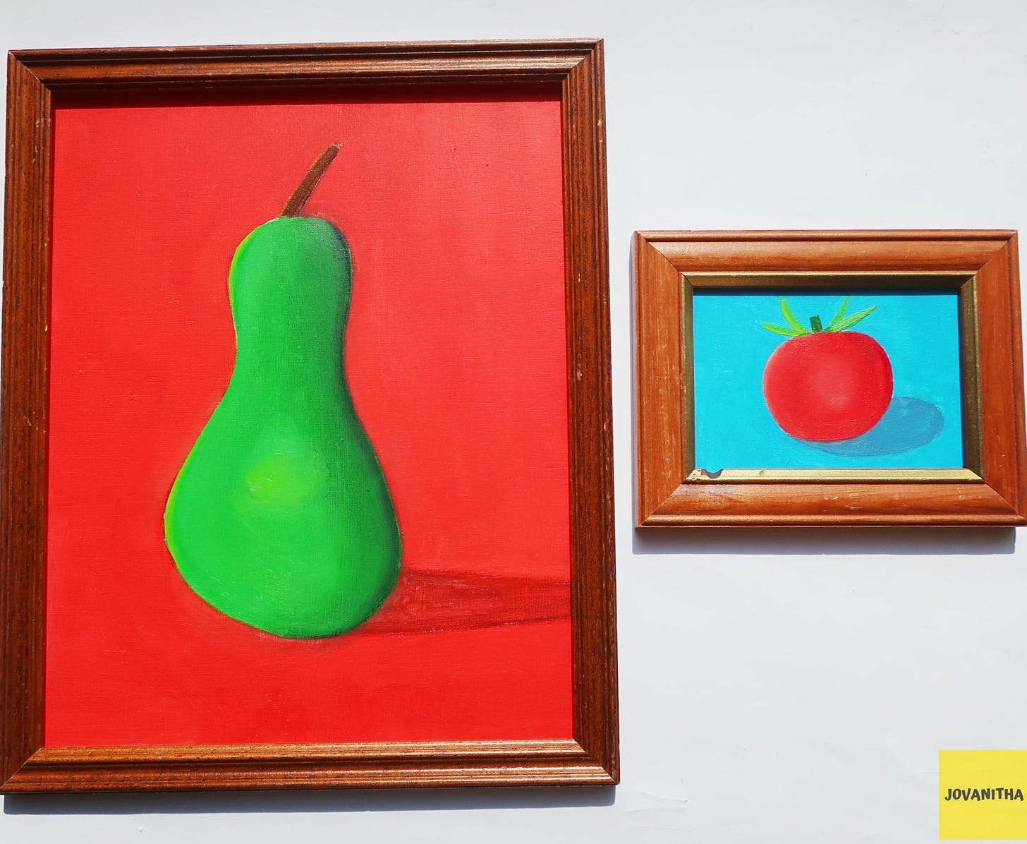 A green pear on a red background and a red tomato on a blue background in thrifted frames