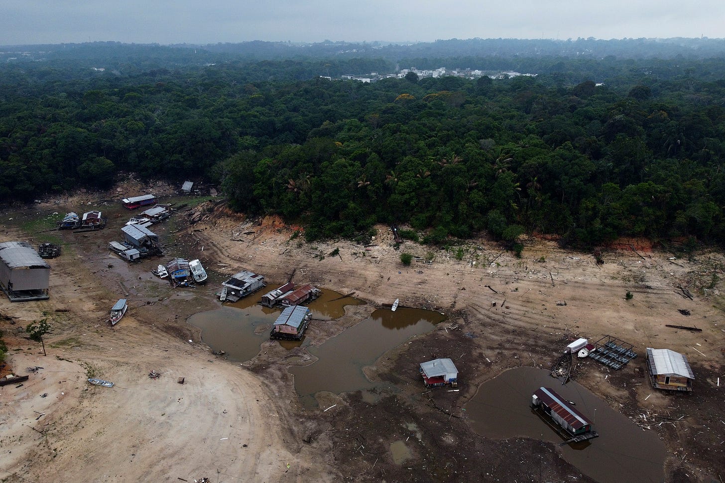 Boats and houseboats are stuck in a dry area of the Negro River during a drought in Manaus, Amazonas state, Brazil, Monday, Oct. 16, 2023. 