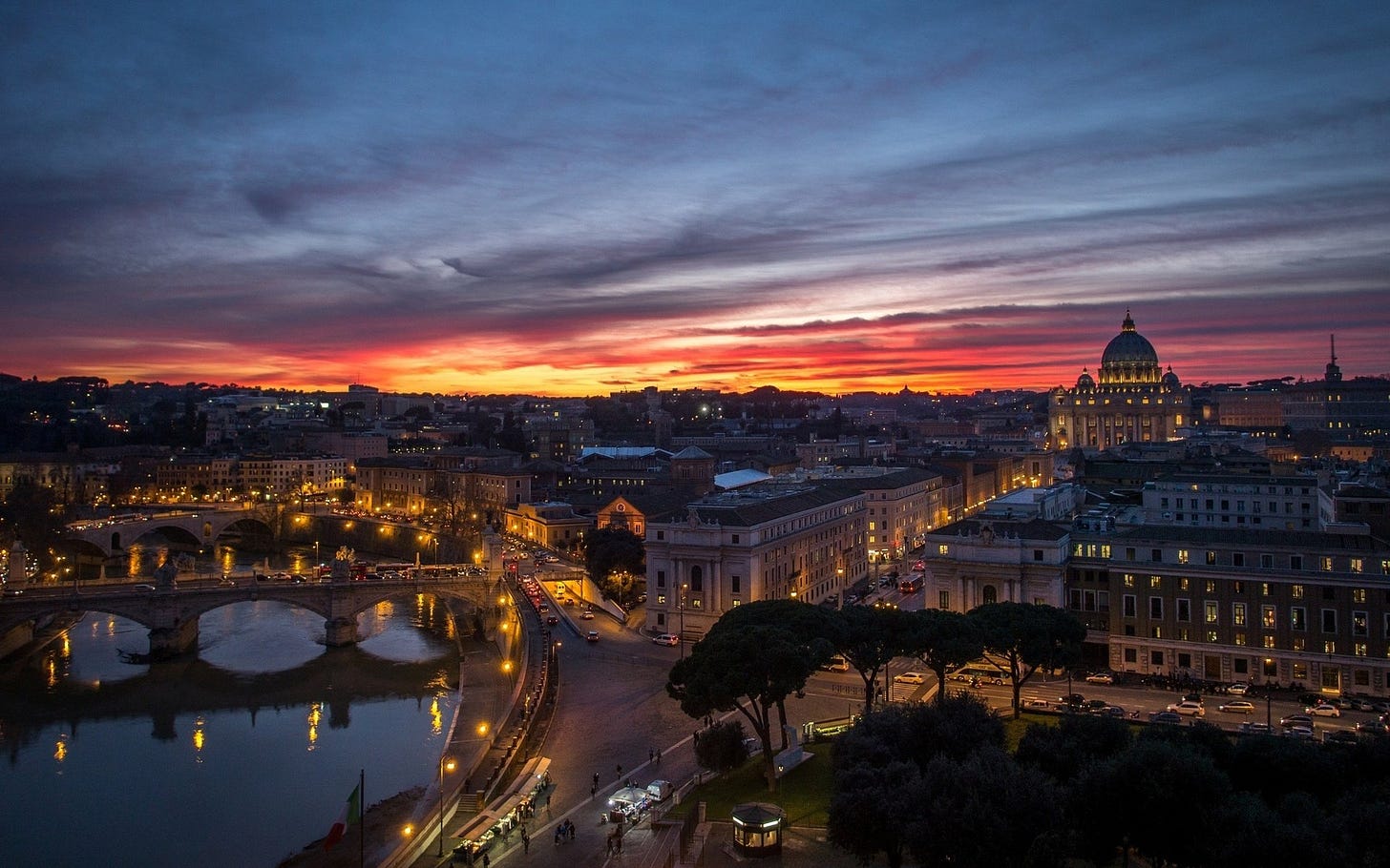 A stunning HD image of Rome at dusk, showcasing the illuminated cityscape against a vibrant sunset backdrop, capturing the essence of its rich history and architecture.