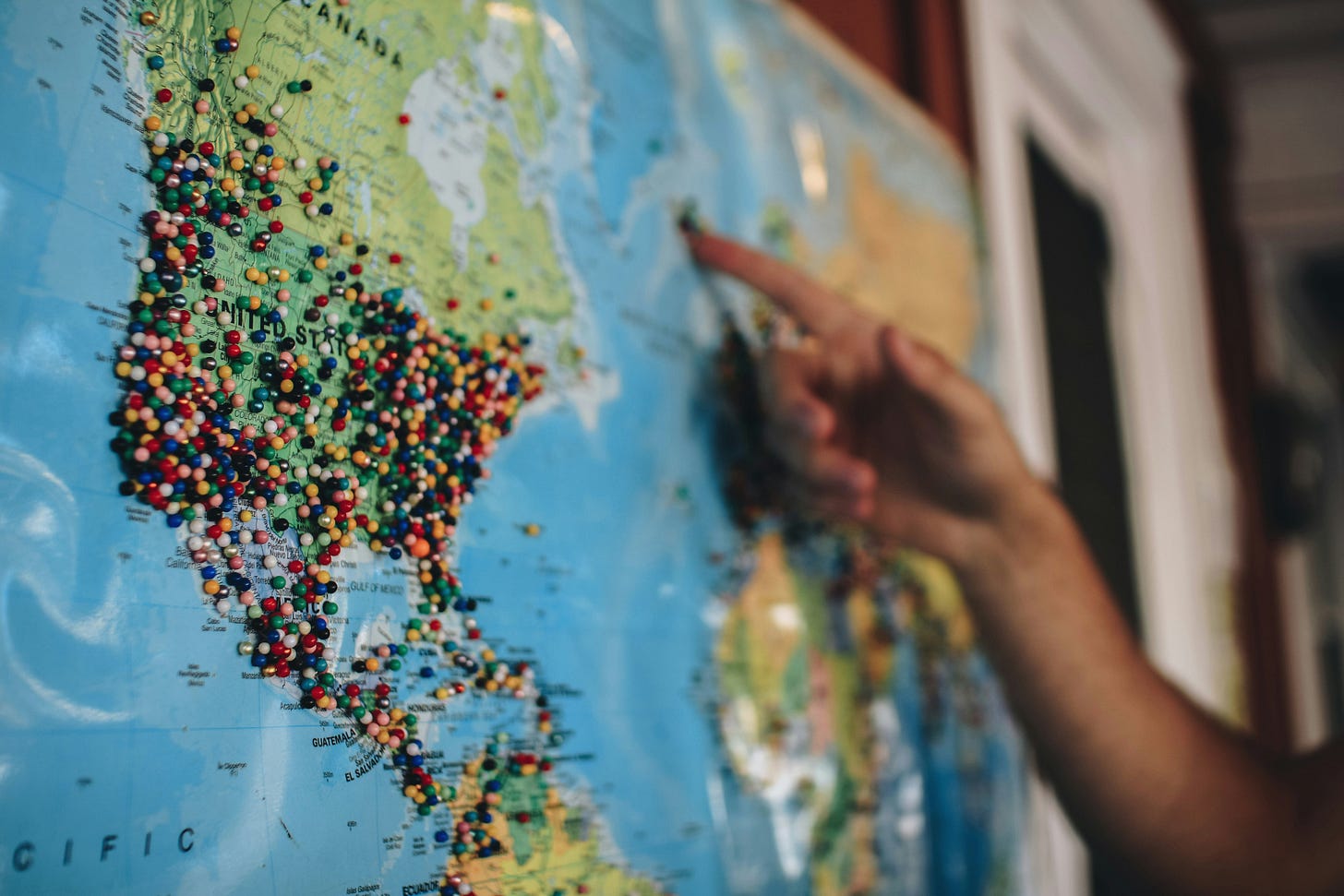 Hand pointing to map of world