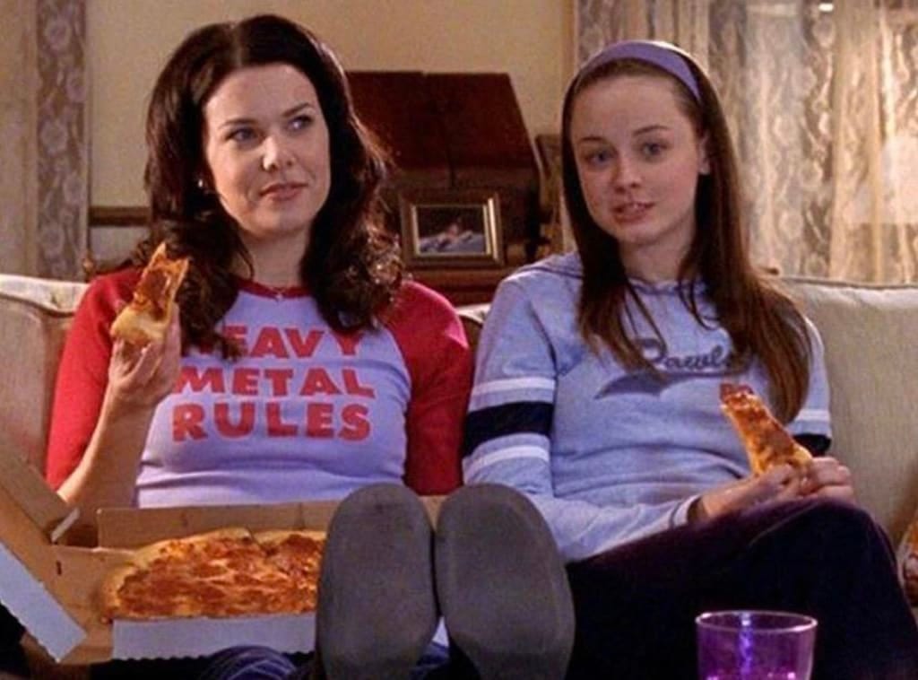 Lorelai and Rory are holding the small slices of pepperoni pizza they're eating from the box.