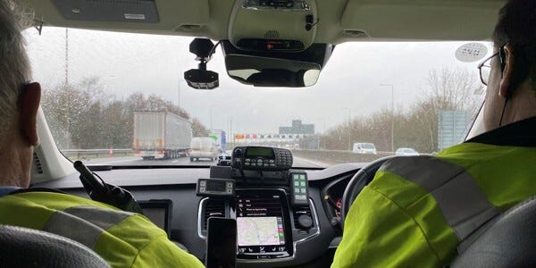 Two officers from the Essex Police Commercial Vehicles Unit traveling in a police car with a view through the windscreen to the motorway