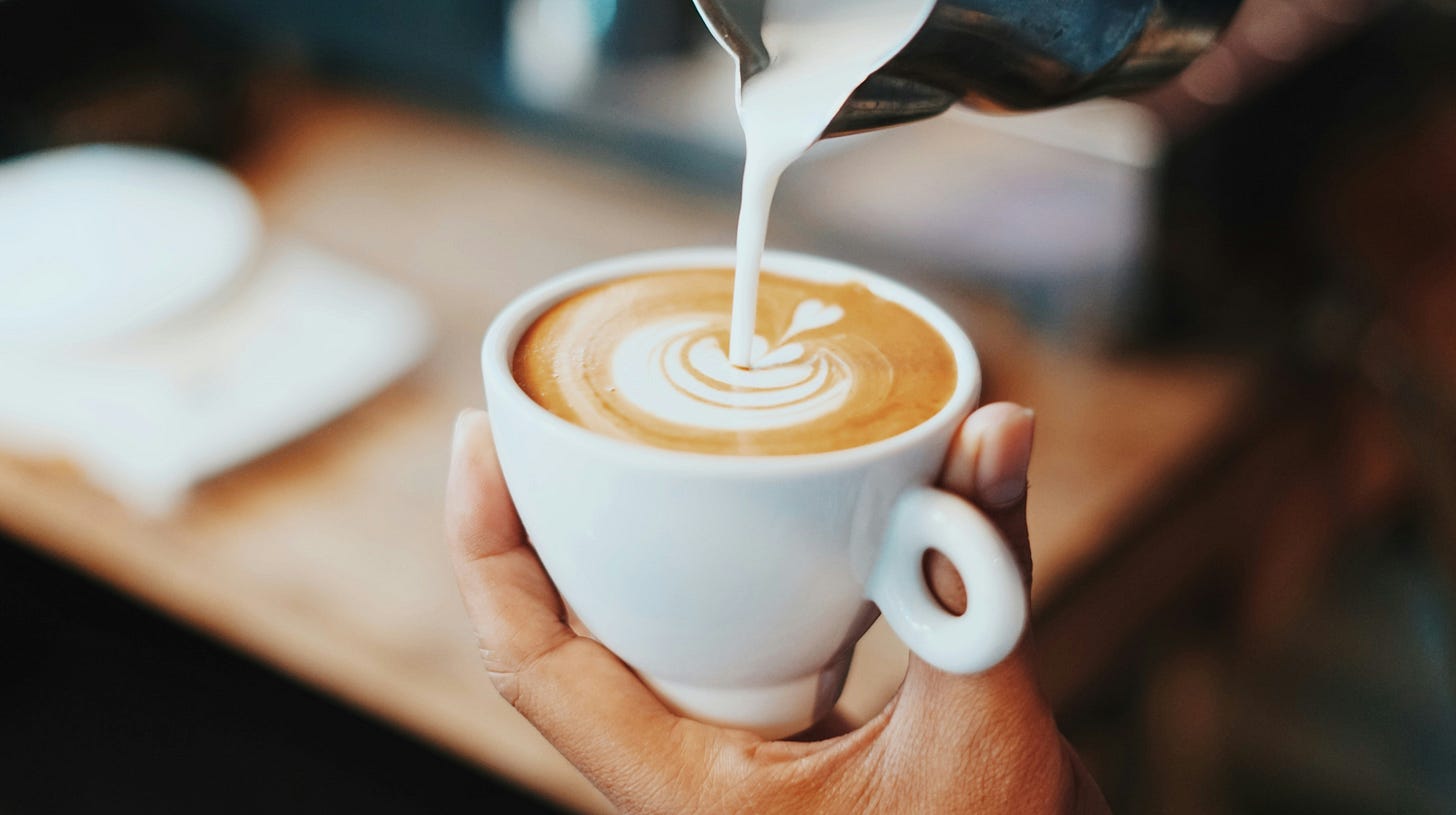 latte with milk being poured into it