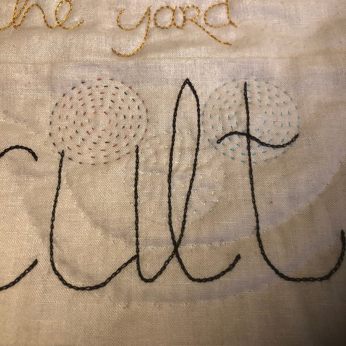 Quilted fabric. Three circles are quilted with red, silver and turquoise, over a part of a word (Occult but here only the cult is showing). 