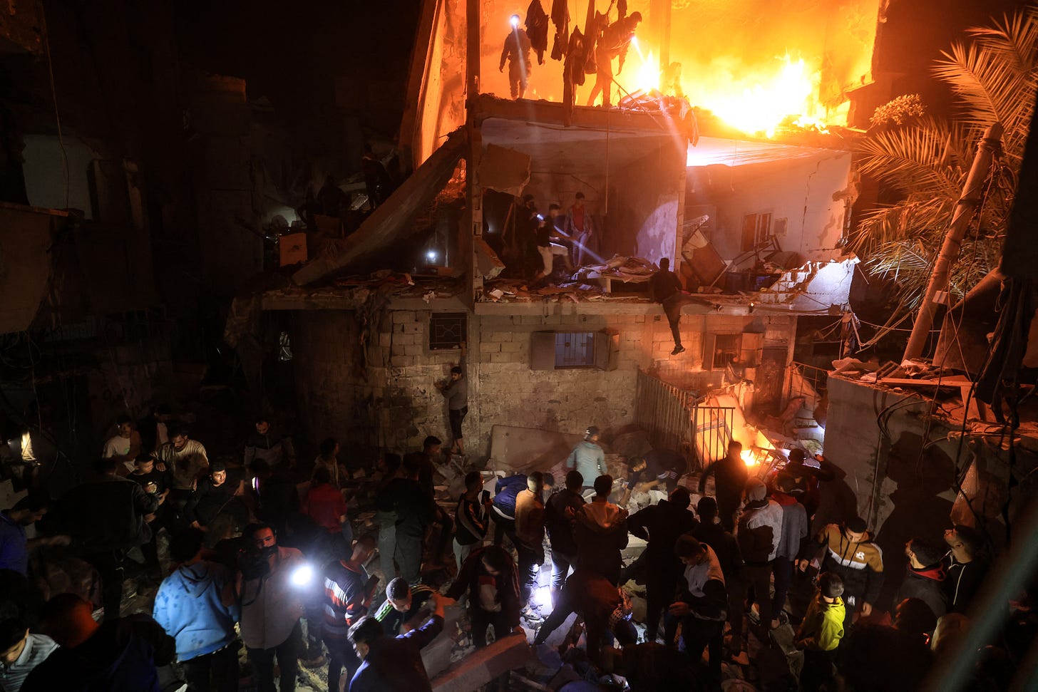 Palestinians search for victims after an Israeli air strike in a still smouldering building