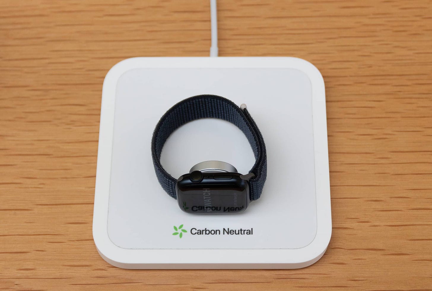 A dock labeled "Carbon Neutral" charges an Apple Watch Series 9 display device at an Apple Store.