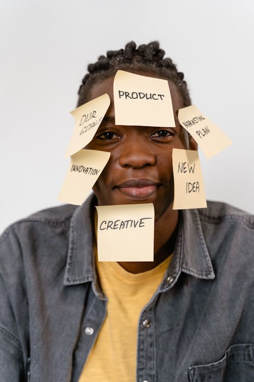 Free Man with sticky notes on face, showcasing innovative ideas in a studio setting. Stock Photo