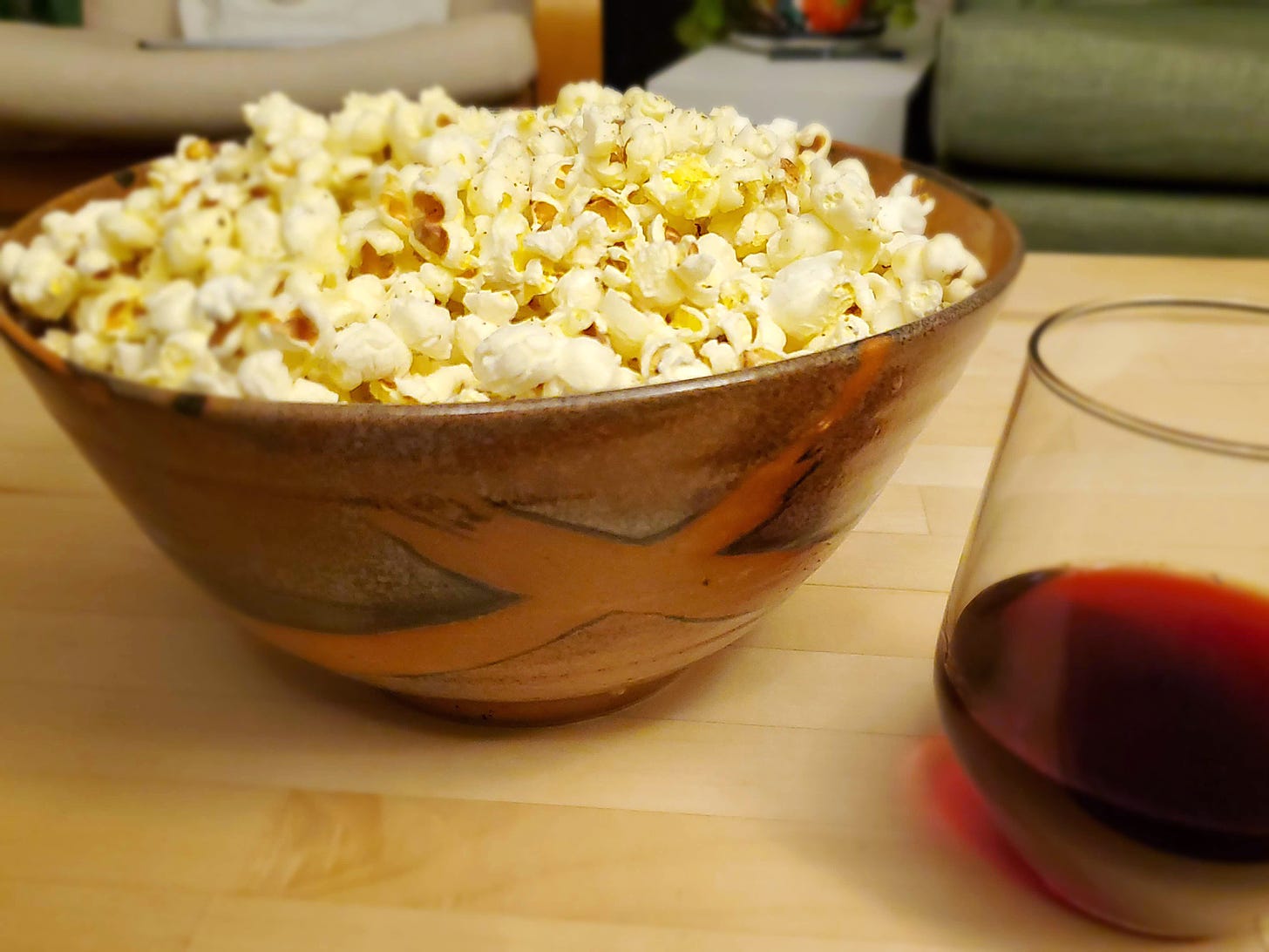 Popcorn piled high in a fancy bowl, with a glass of wine
