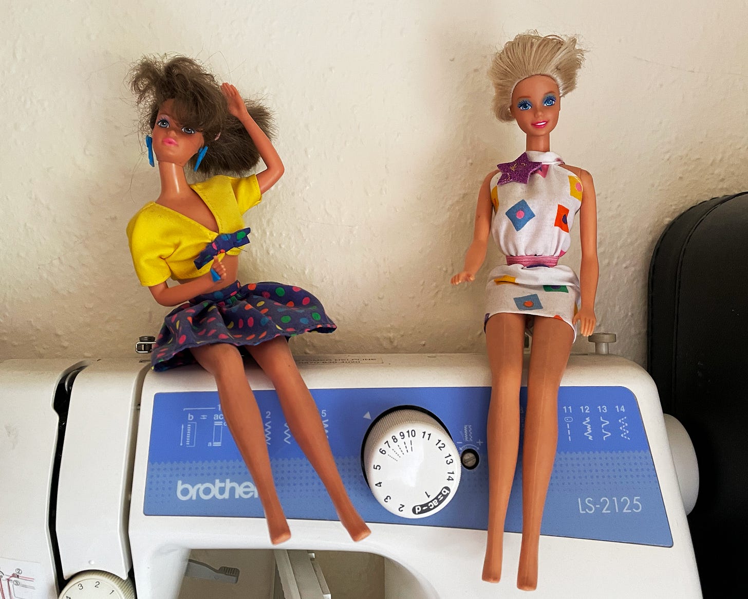 Two Barbie dolls from the 80's sat onto of a dusty sewing machine.